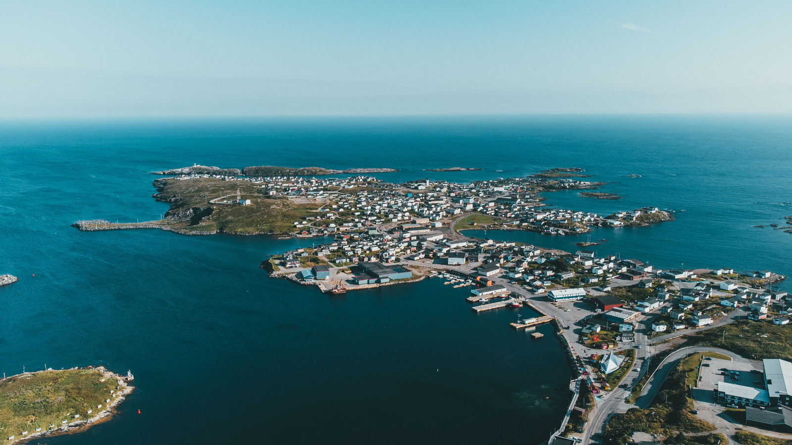 An aerial view of a small coastal town built on a rocky island, surrounded by open sea