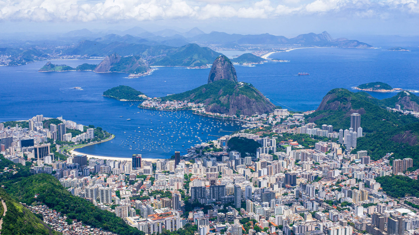 Aerial view of Rio de Janeiro's Guanabara Bay with Sugarloaf Mountain rising above the dense coastal city and surrounding hills